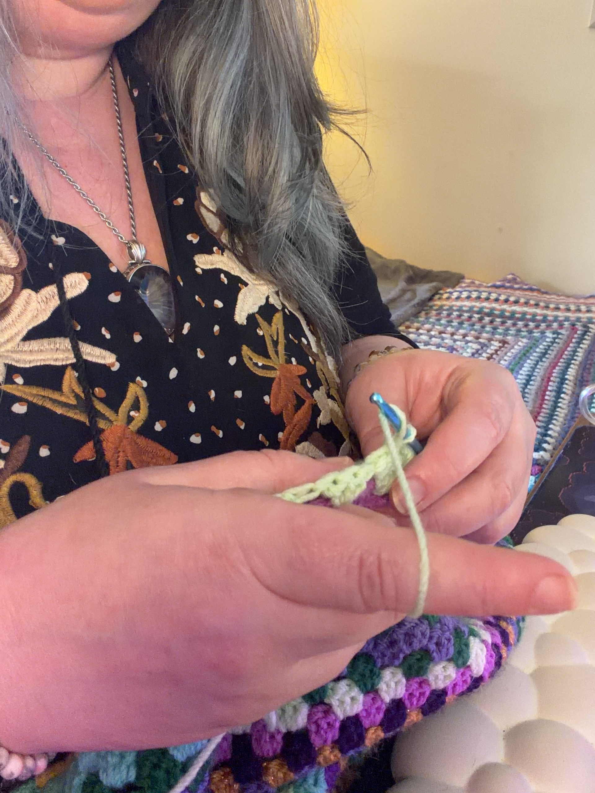 Hands crocheting with colourful yarn