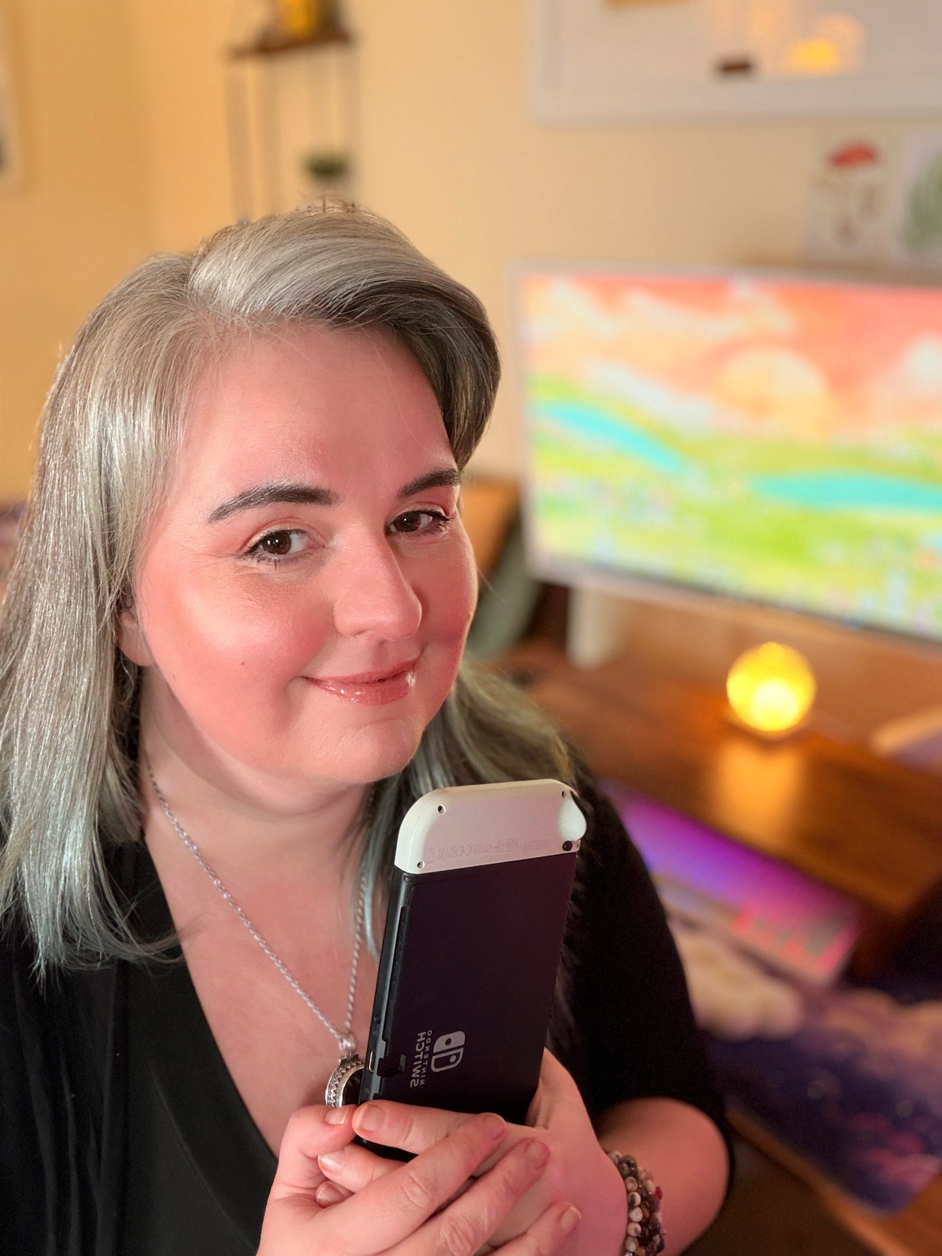 this is novachasing at her desk, with a switch in her hands. with her gaming gaming set up in the background